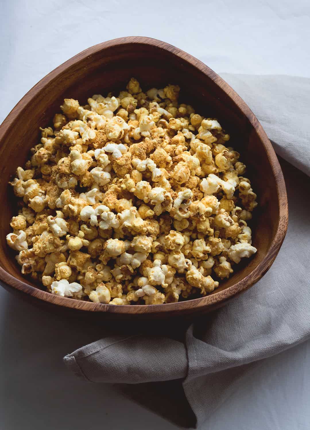 Cheesy Vegan Popcorn - a delicious healthy twist on the classic. Popped the old-fashioned way on the stove with coconut oil and then spiced to perfecting. Ridiculously easy to make! | thehealthfulideas.com