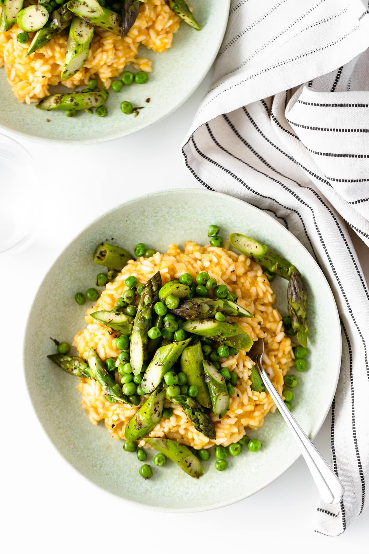 A shot of arborio risotto from above served with asparagus and peas