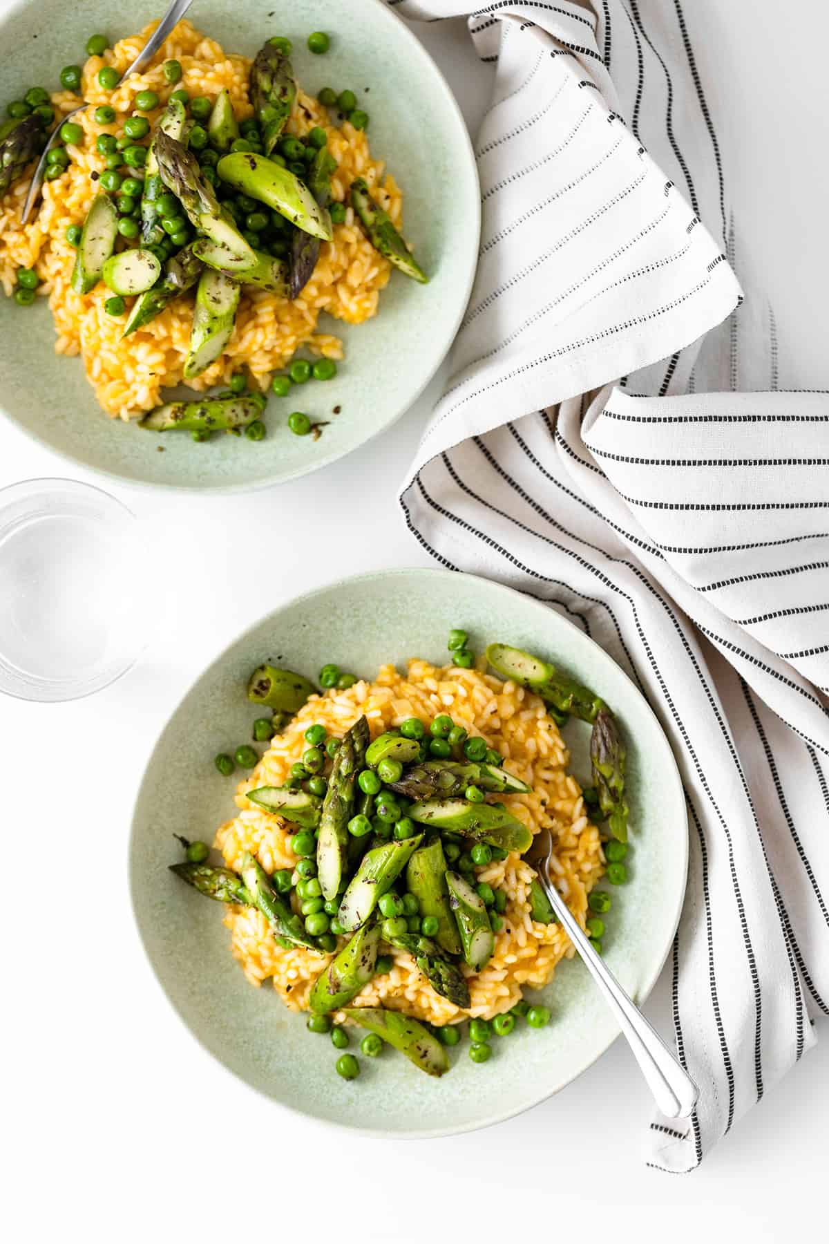 A shot of arborio risotto from above served with asparagus and peas