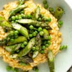 A shot of arborio risotto from above served with asparagus and peas