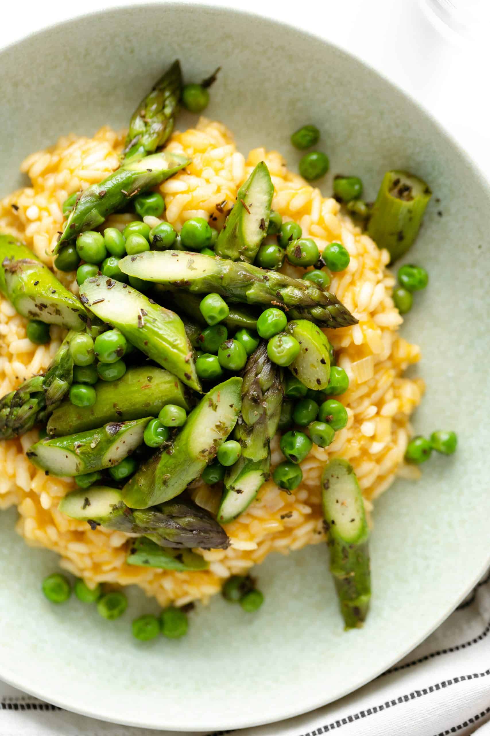 A shot of arborio risotto from above served with asparagus and peas