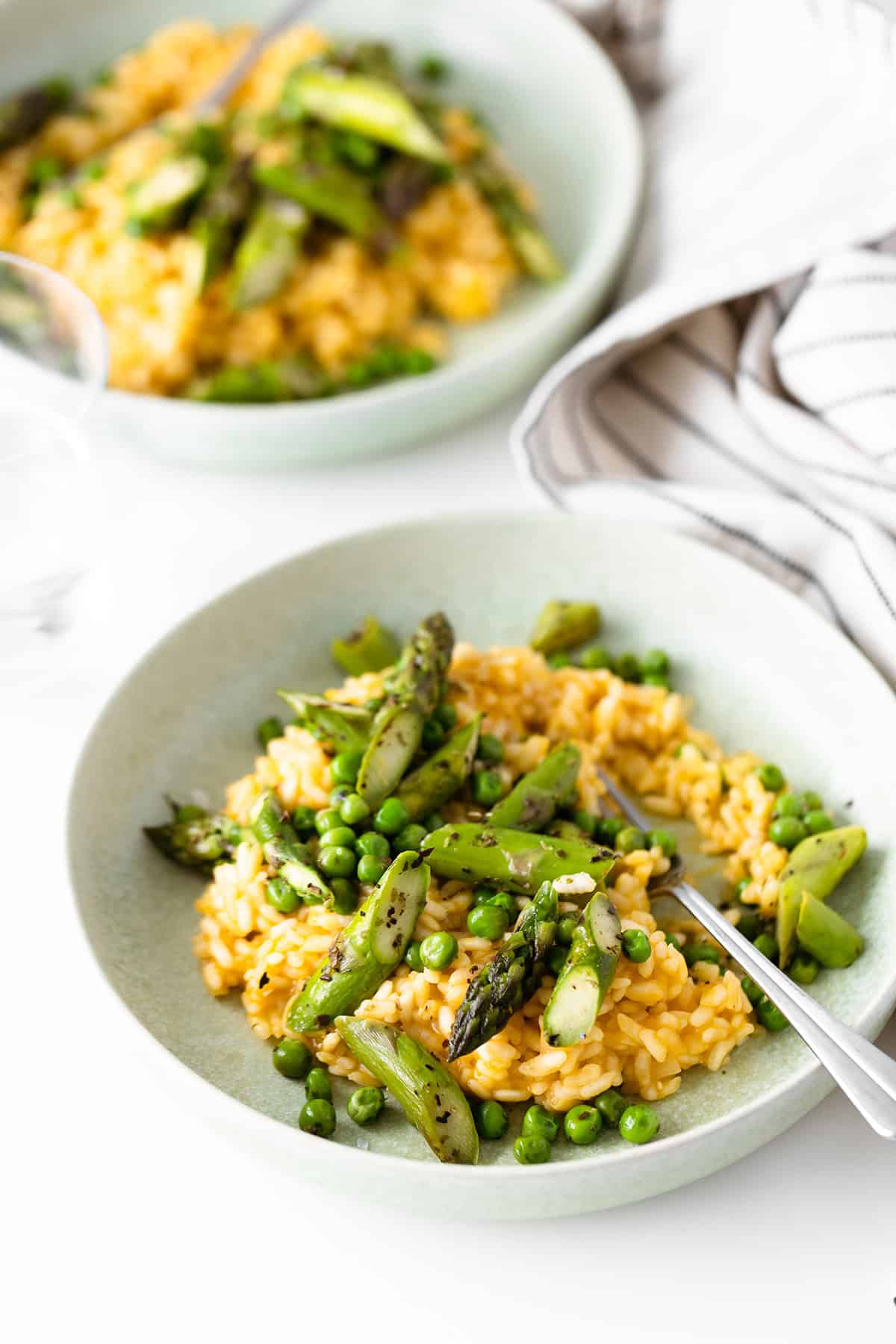 A shot of arborio risotto from above served with asparagus and peas