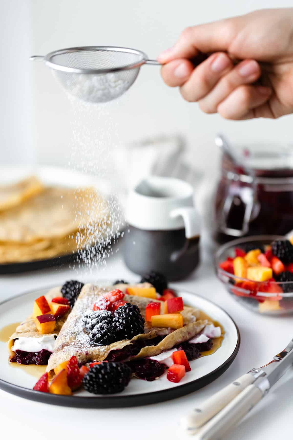 Sugar being dusted over some gluten-free Crepes with Lavender Blackberry Jam