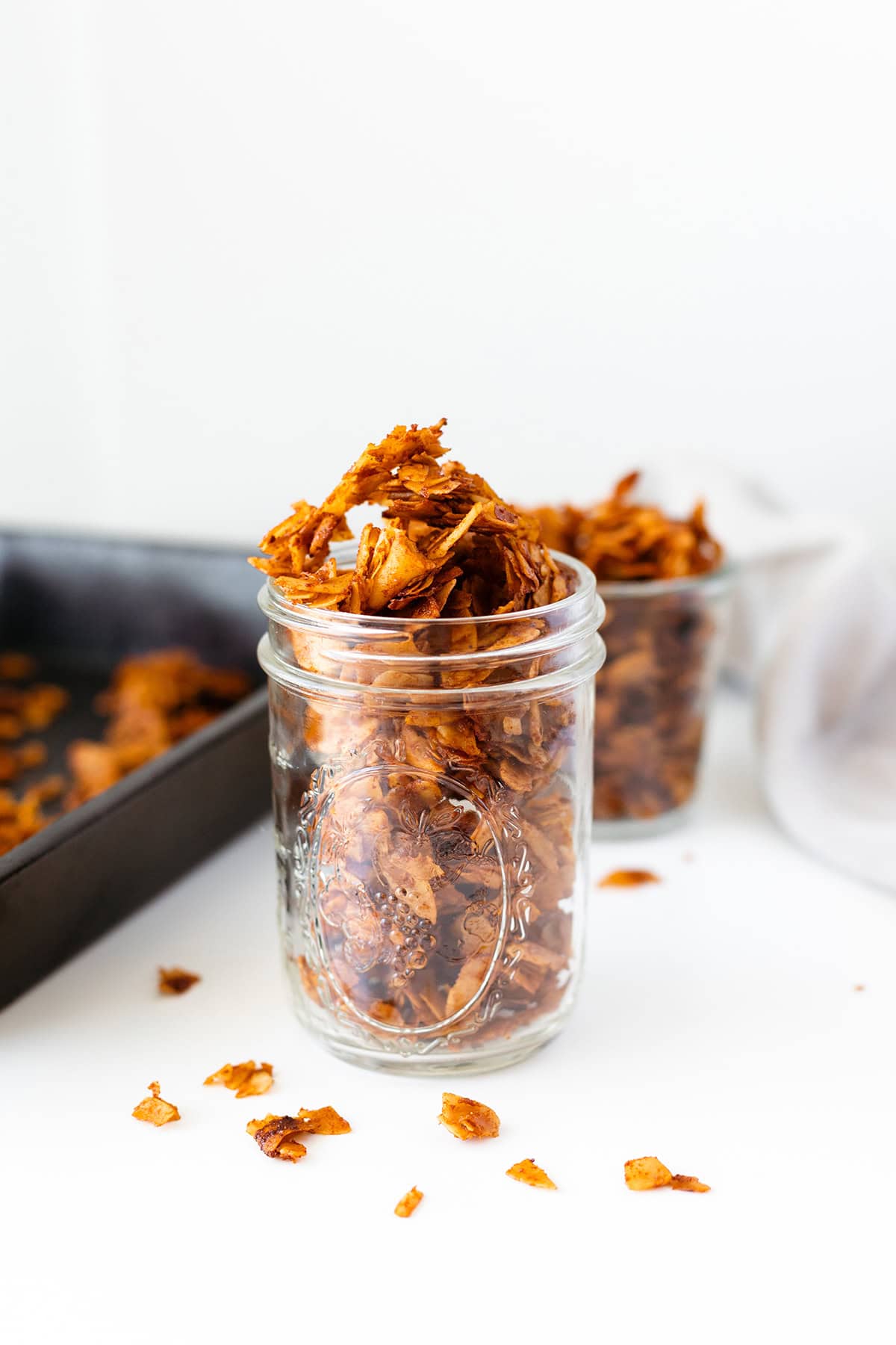 Vegan coconut bacon in a glass jar with a baking sheet in the background