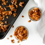 Overhead shot of vegan coconut bacon in a glass jar and on a baking pan