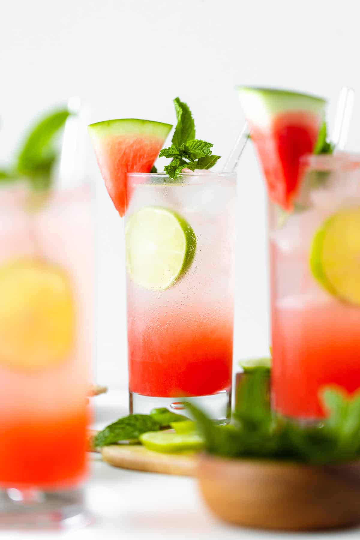 Watermelon Coconut Rum Cooler - three glasses in shot, head on, decorated with mint, lime, and watermelon slice