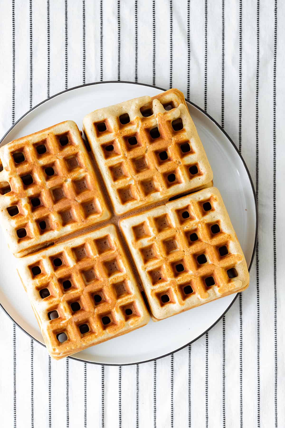 4 Basic Gluten-free Waffles on a white plate and a white table cloth with black stripes