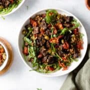 Za'atar Roasted Eggplant Lentil Salad with Sundried Tomatoes in white bowl on a grey background