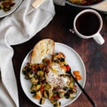 A photo of Bell Pepper and Zucchini Breakfast Skillet with Za'atar on a white plate and a wooden table