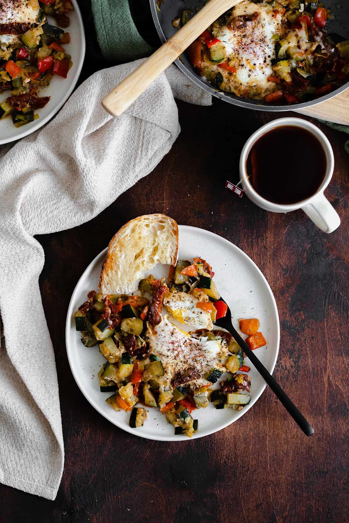 A photo of Bell Pepper and Zucchini Breakfast Skillet with Za'atar on a white plate and a wooden table