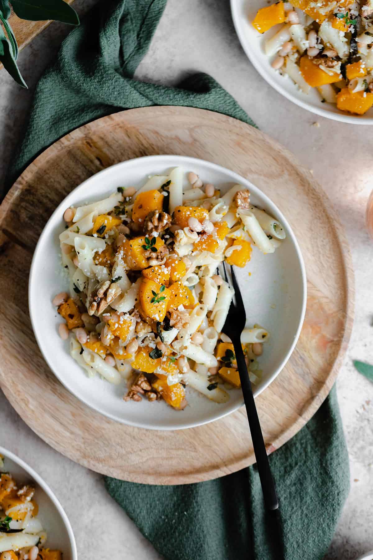 A vertical overhead shot of Butternut Squash Penne with Sage and Toasted Walnuts on a white plate