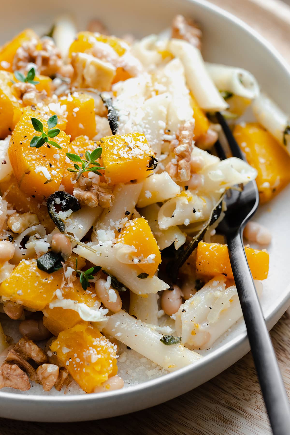 A vertical shot of Butternut Squash Penne with Sage and Toasted Walnuts on a white plate