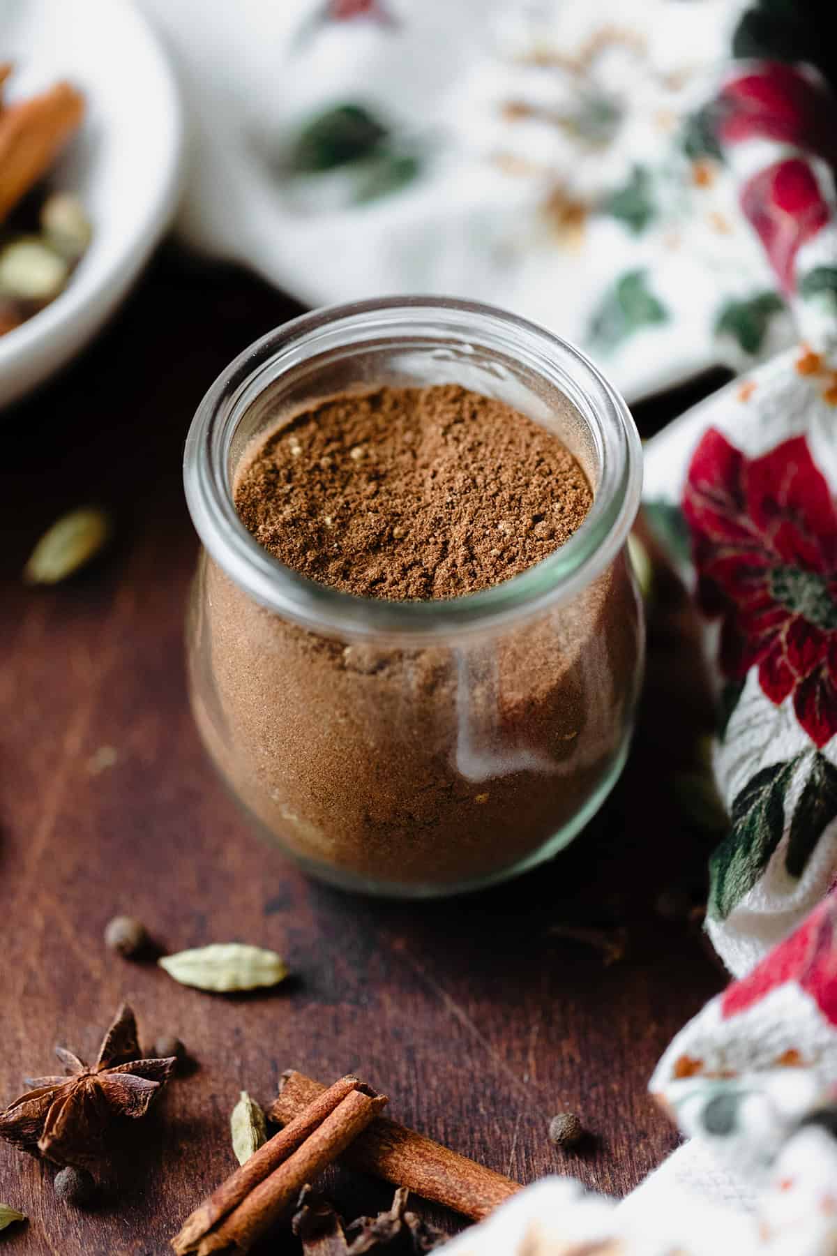 A photo of all the spices used in the Christmas Spice Blend on a white plate. On a dark wooden background.