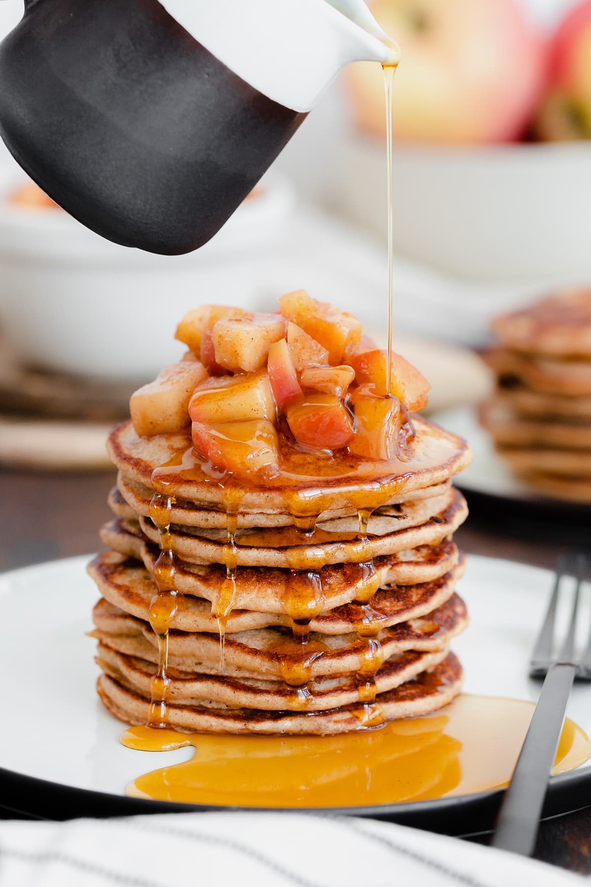 A straight on photo of Chocolate Chip Apple Cider Pancakes with Stewed Apples on a white plate and dark wooden background.