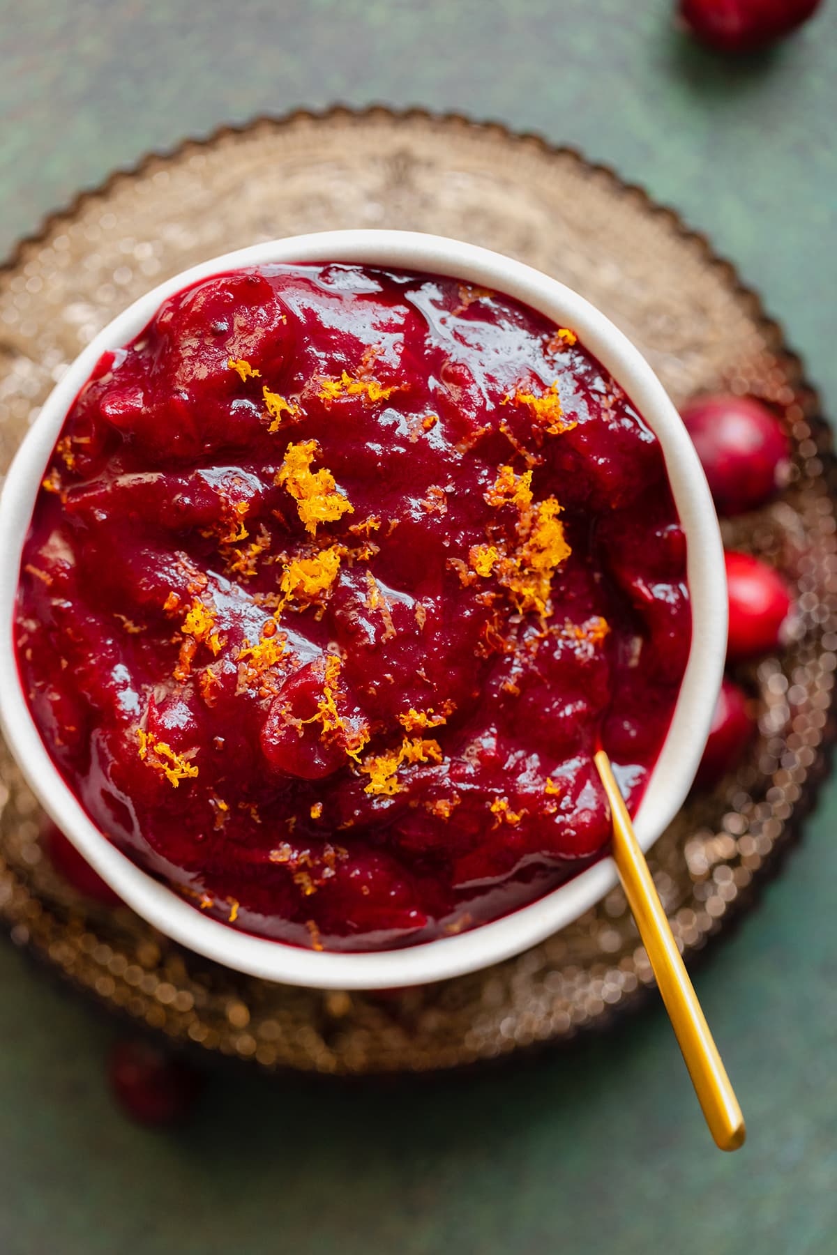 An overhead close up shot of Orange Maple Cranberry Sauce in a white bowl on a green background