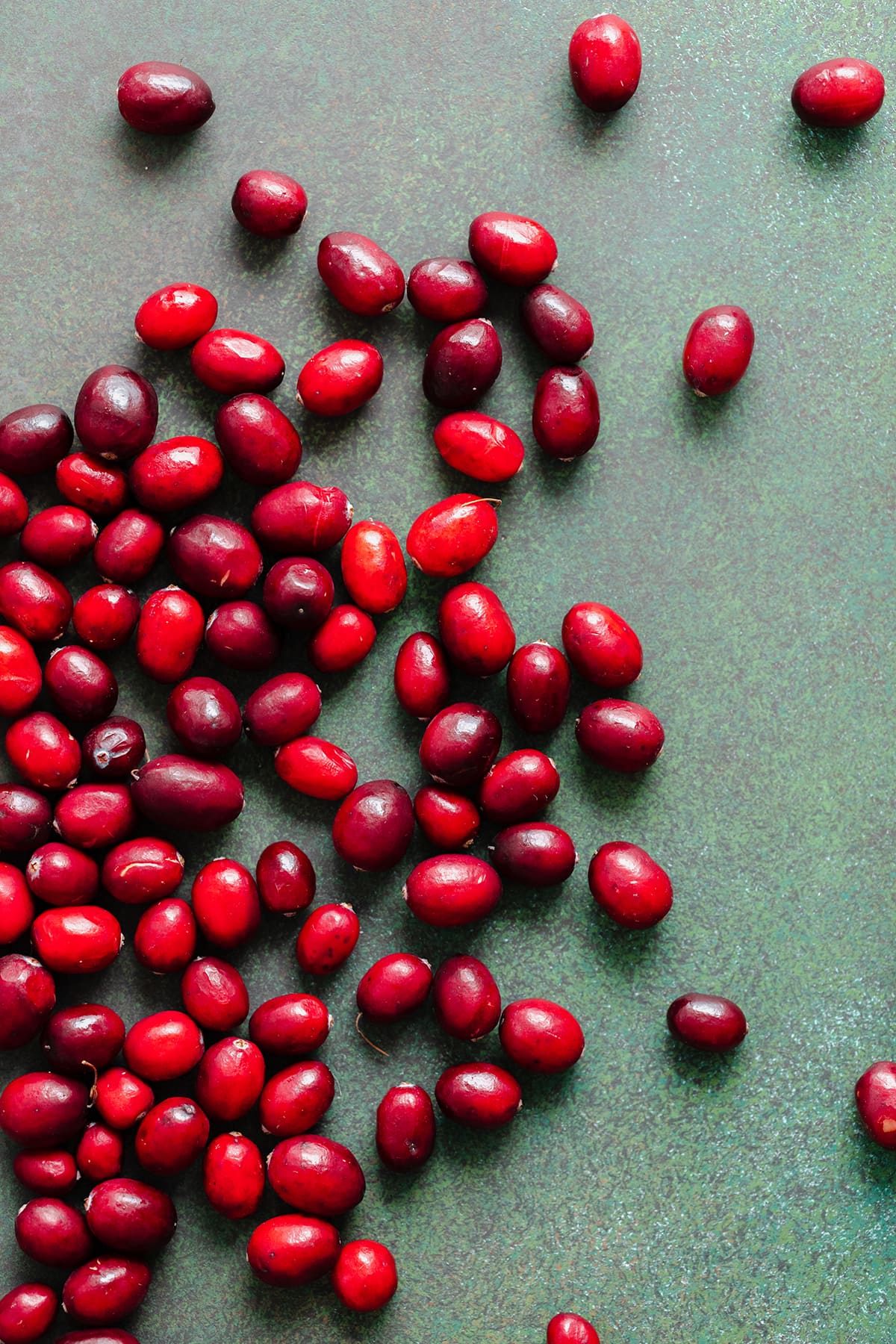 A photo of raw cranberries on a green background