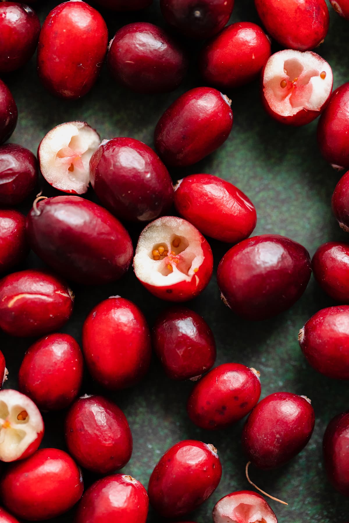 A close up photo of raw cranberries on a green background