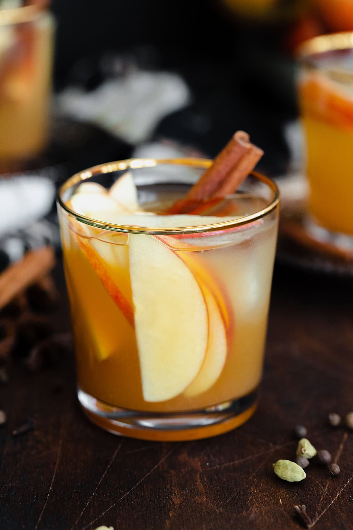 A straight on photo of Spiced Rum Apple Cider Cocktail in a short glass with a golden rim