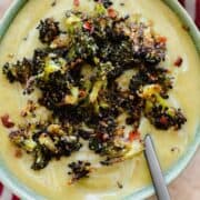 An overhead shot of Cream of Broccoli Soup with Roasted Broccoli Croutons on a striped red and white tea towel and green background