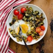An overhead shot of Leek and Zucchini Egg Skillet on a red and white striped kitchen towel and wooden table