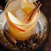 A straight on photo of Spiced Rum Apple Cider Cocktail in a short glass with a golden rim