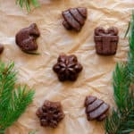 Chocolate Hazelnut Fudge Bites laid out on parchment paper, with fir twigs around the bites.