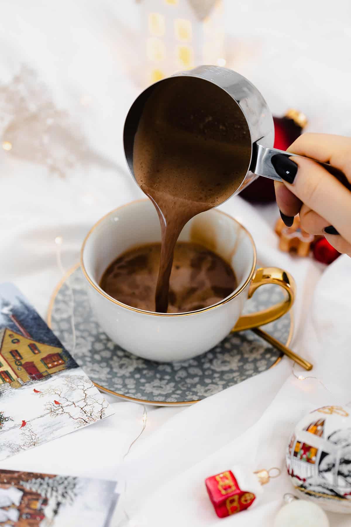 Vegan Eggnog Mocha with whipped cream and a sprinkle of nutmeg in a white mug on white bedsheets.