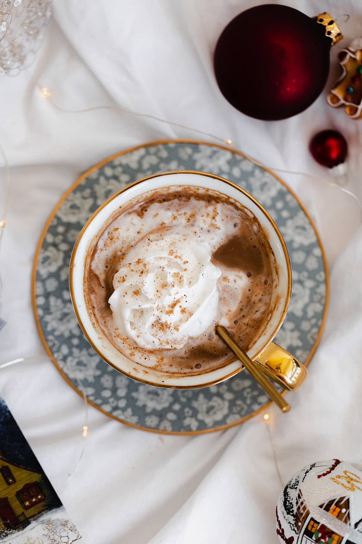 Vegan Eggnog Mocha with whipped cream and a sprinkle of nutmeg in a white mug on white bedsheets.