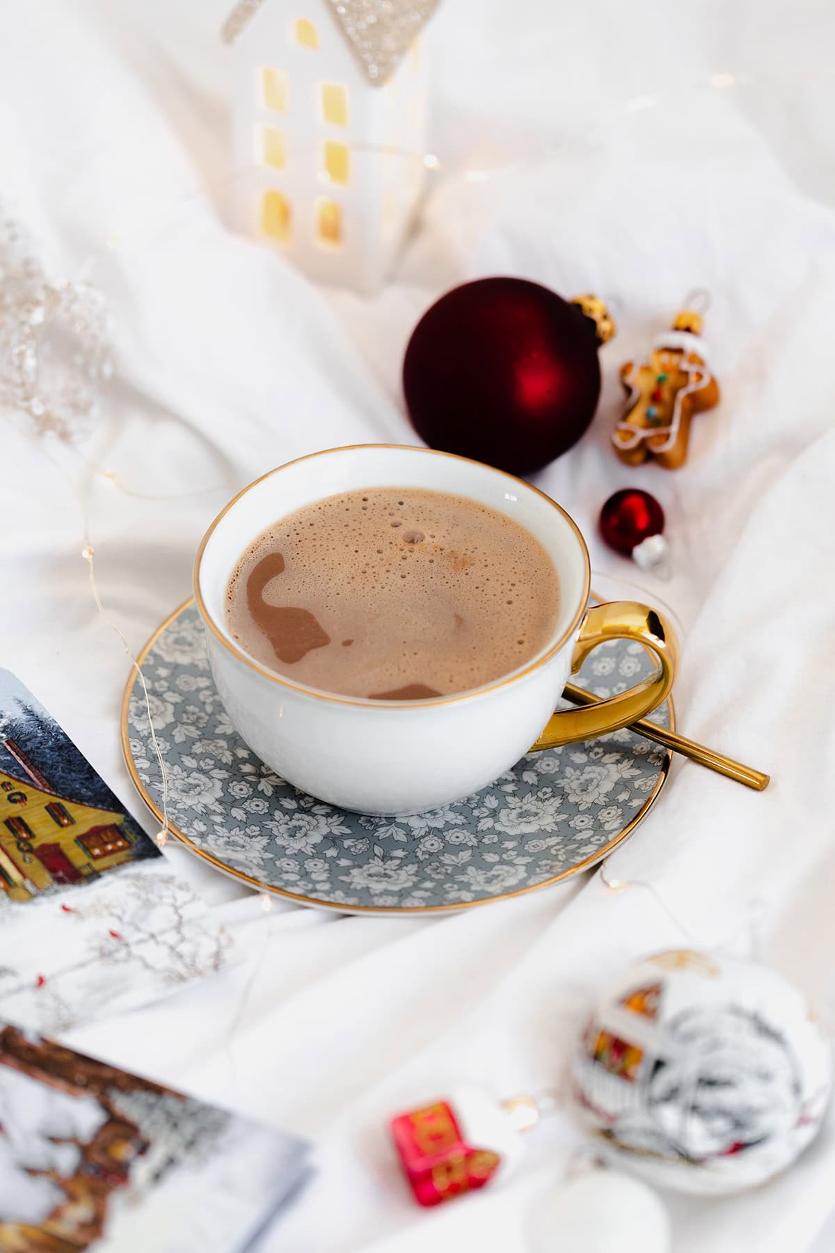 Vegan Eggnog Mocha with whipped cream and a sprinkle of nutmeg in a white mug on white bedsheets.