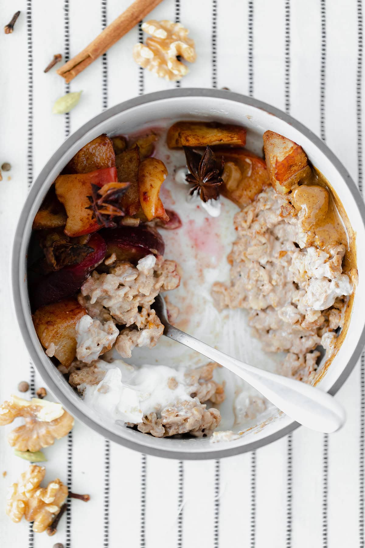 Winter Spiced Oatmeal with Roasted Fruit on a white tablecloth with black stripes.