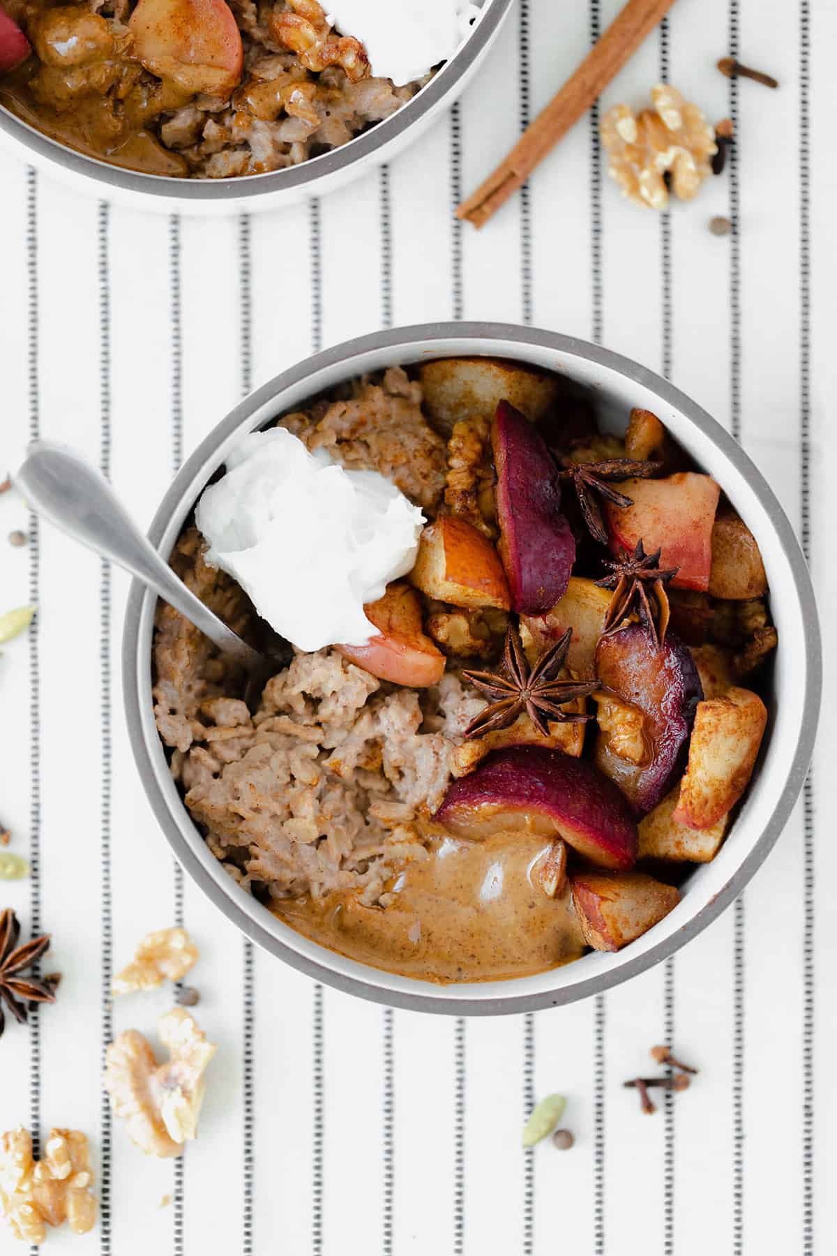 Winter Spiced Oatmeal with Roasted Fruit on a white tablecloth with black stripes.