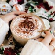 A shot of Christmas Spiced Hot Chocolate with whipped cream, dusted with gingerbread spice in a beige cup.