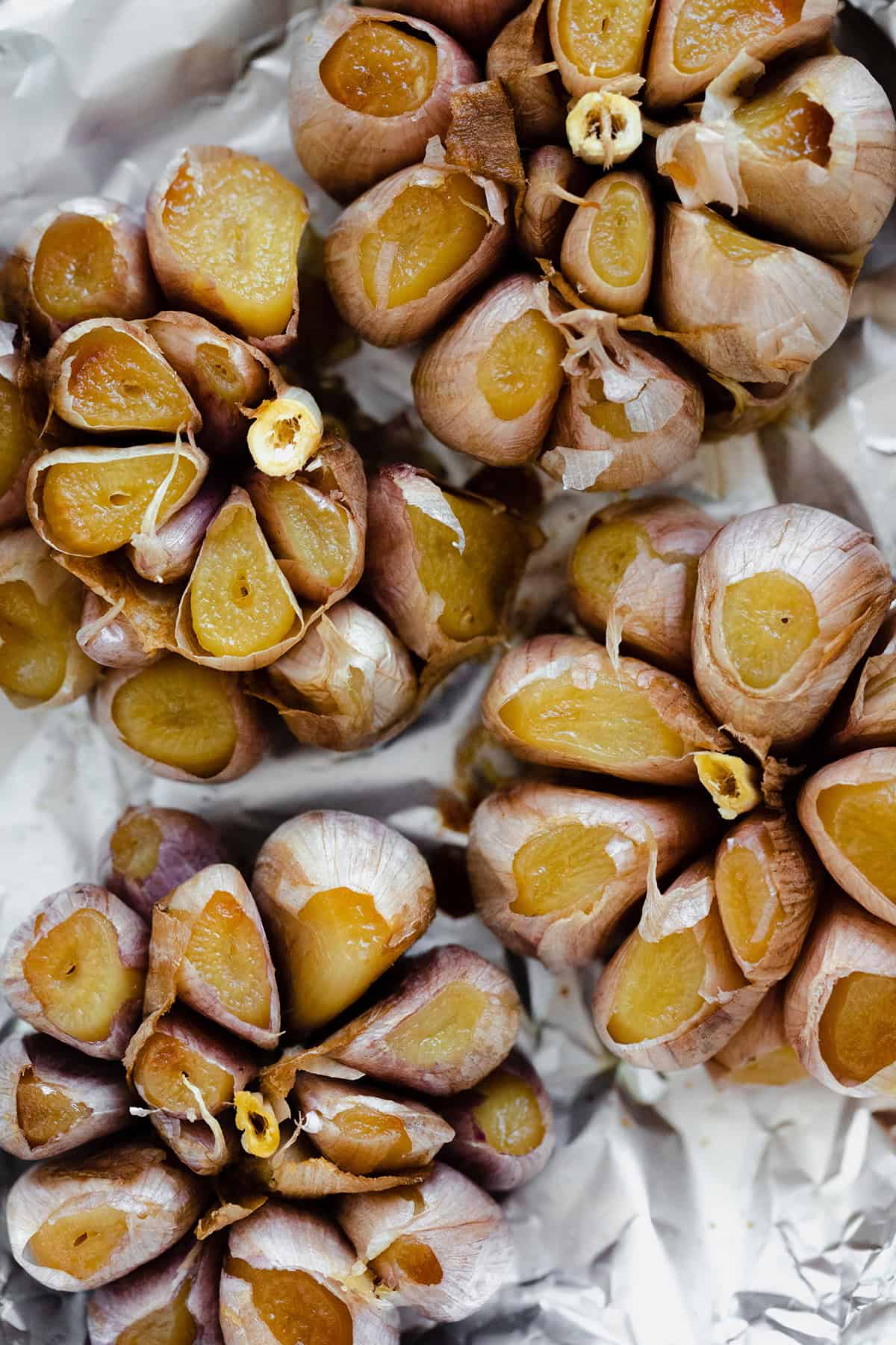 A close up shot of roasted garlic bulbs with the tops cut off.