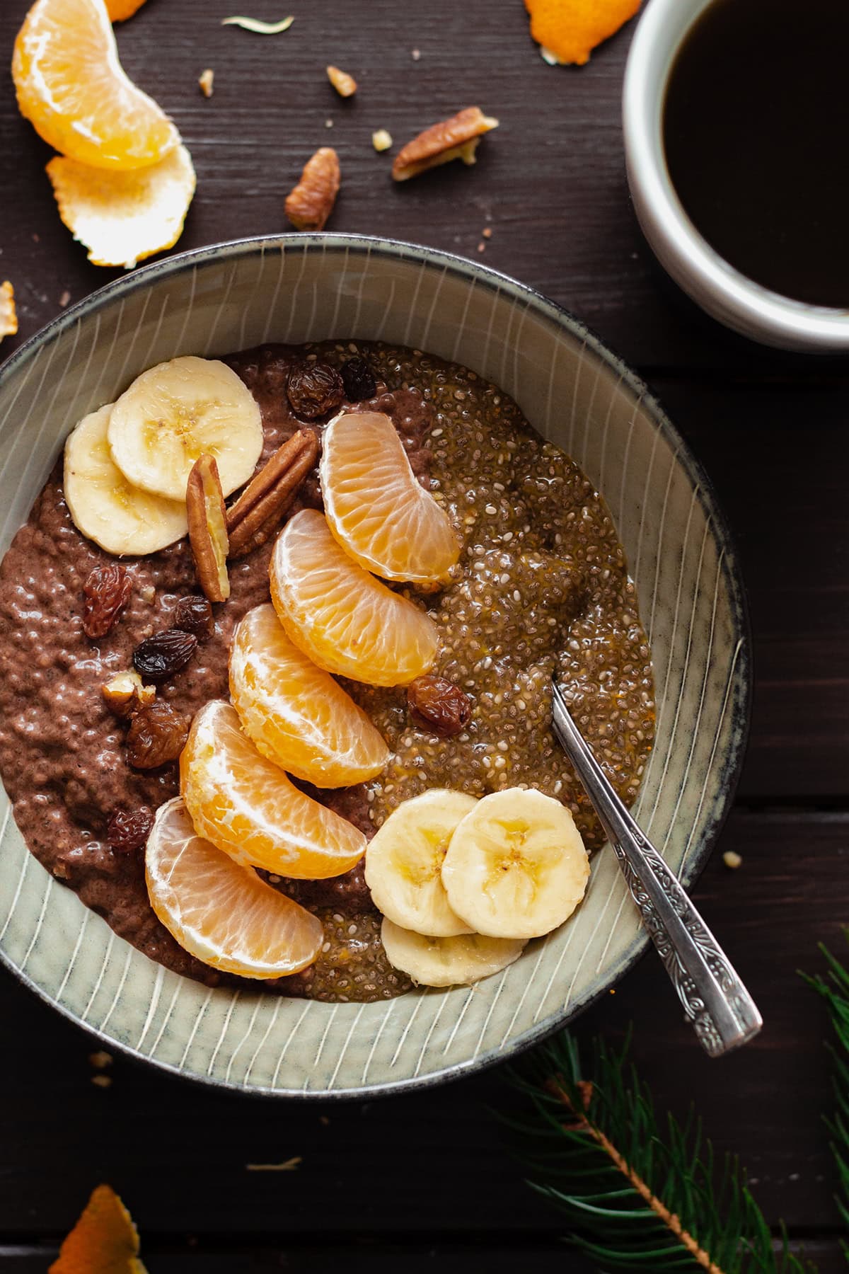 Tangerine Chocolate Chia Pudding in a bowl on a dark wooden table with a cup of coffee on the left.