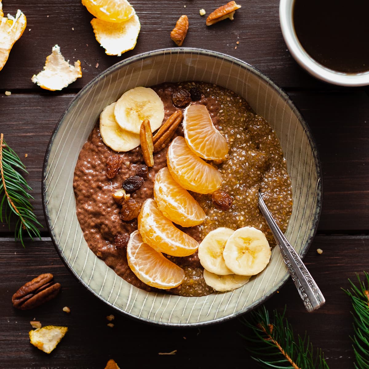 Tangerine Chocolate Chia Pudding in a bowl on a dark wooden table with a cup of coffee on the left.