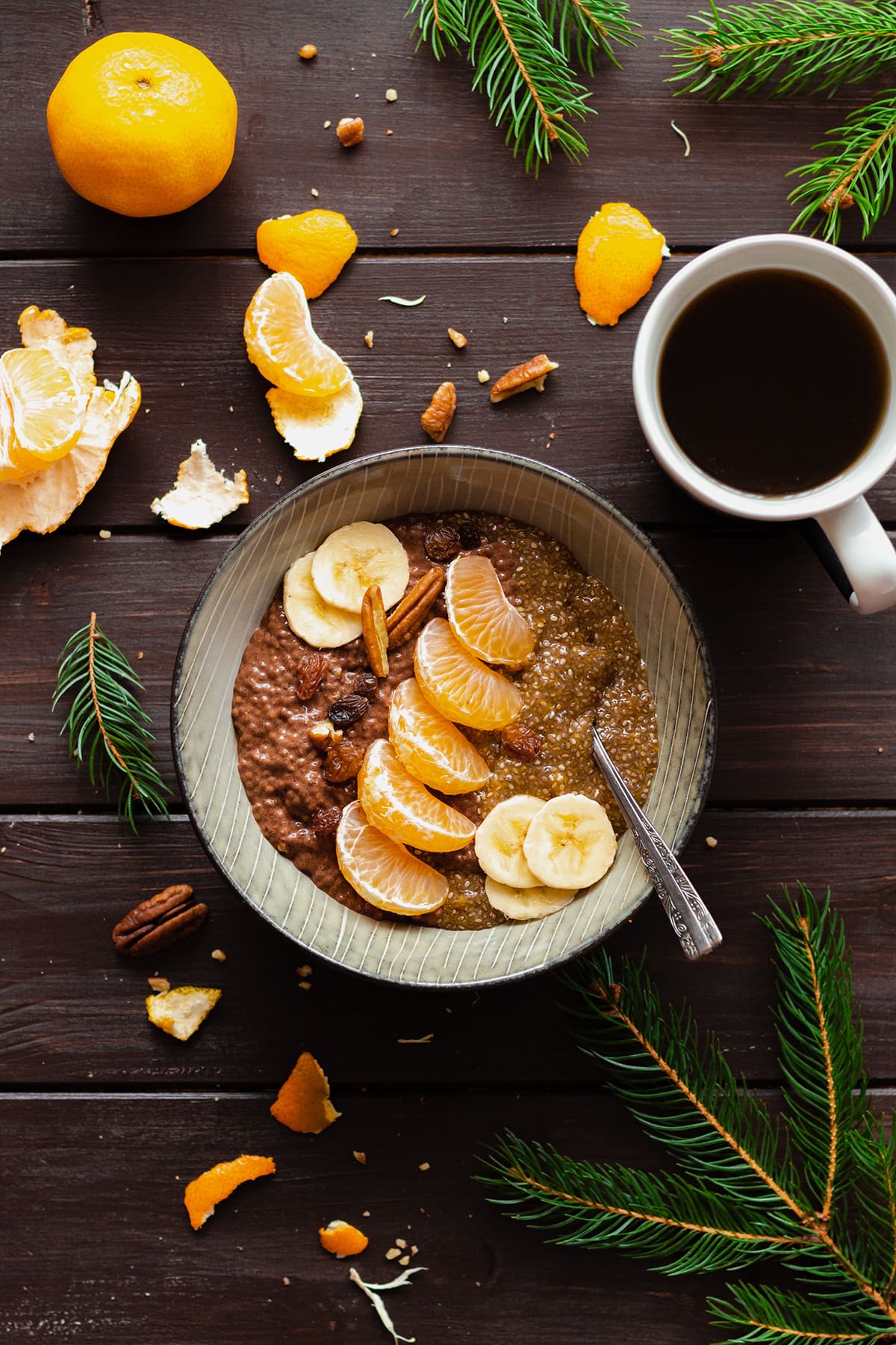 Tangerine Chocolate Chia Pudding in a bowl on a dark wooden table with a cup of coffee on the left.