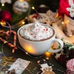 Peppermint hot chocolate in a white cup topped with whipped cream and crushed candy cane.