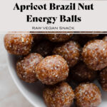 Close up of energy balls in a white bowl on a marble counter. Title of the recipe in photo.