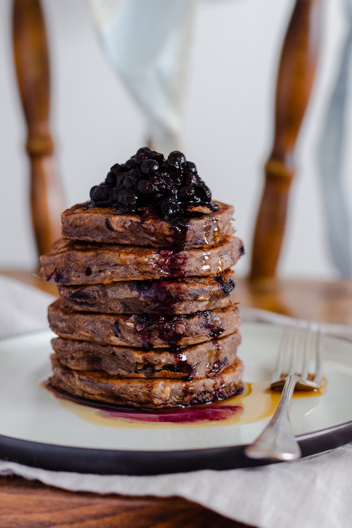 Buckwheat banana blueberry pancakes stacked on a beige plate on a chair.