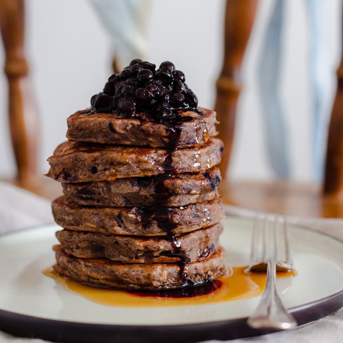 Buckwheat banana pancakes stacked on a beige plate on a chair.