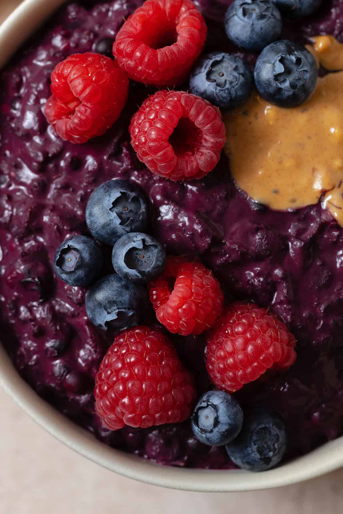 A close up of Maqui Berry oatmeal topped with berries and peanut butter.