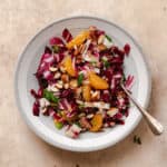 Radicchio Clementine Salad shown on a shallow grey bowl with a white stripe along the edge. Fork resting on the right side of the bowl in the salad.