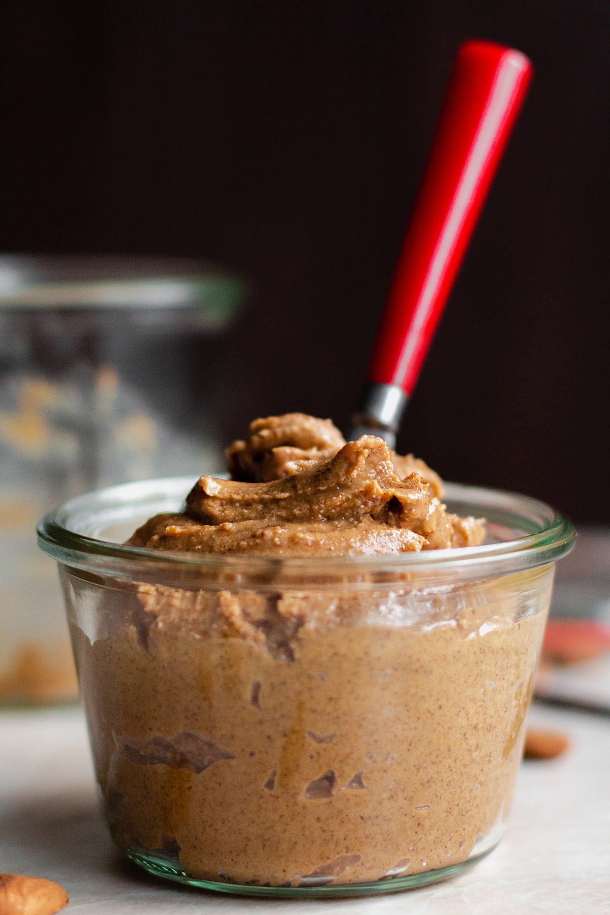 Salted Caramel Nut Butter in a glass jar with a red spoon.