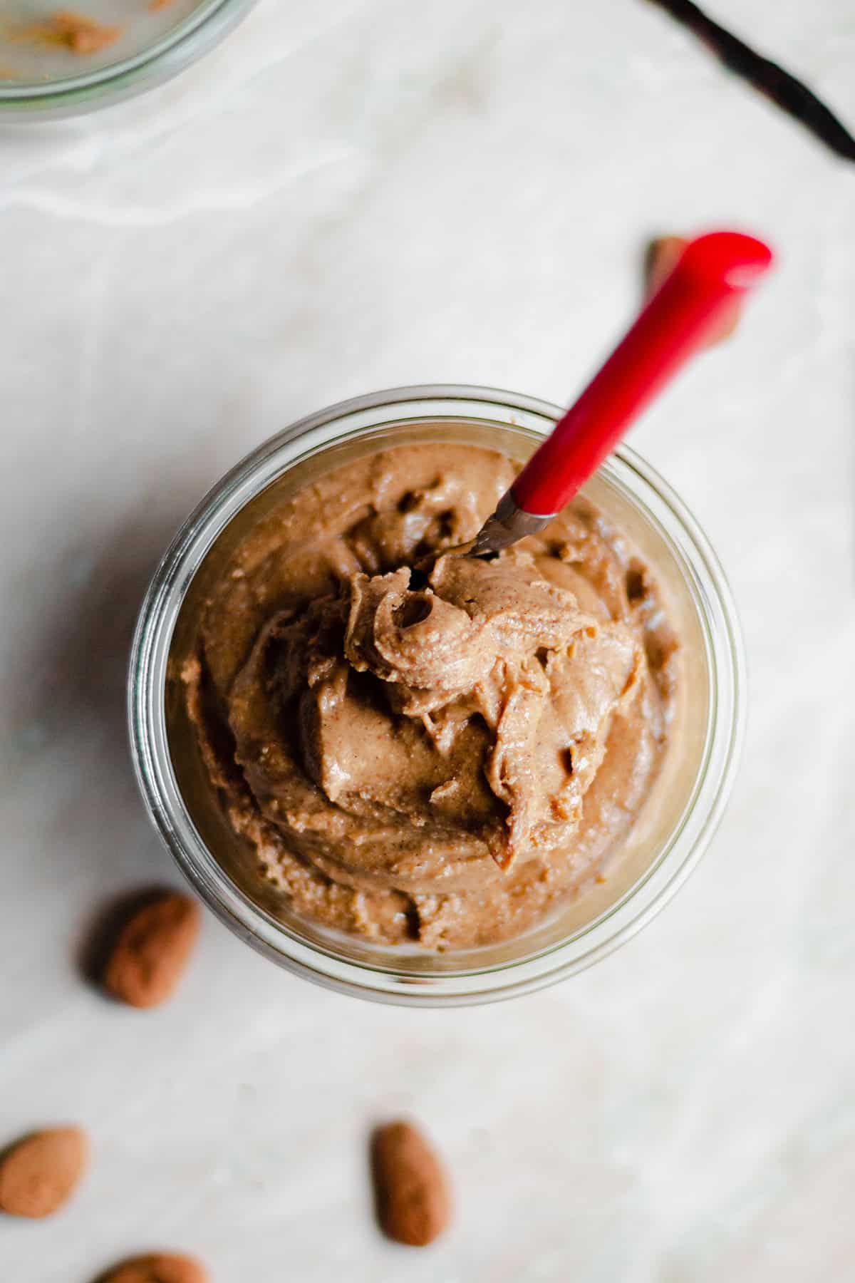 Salted Caramel Nut Butter in a glass jar with a red spoon.