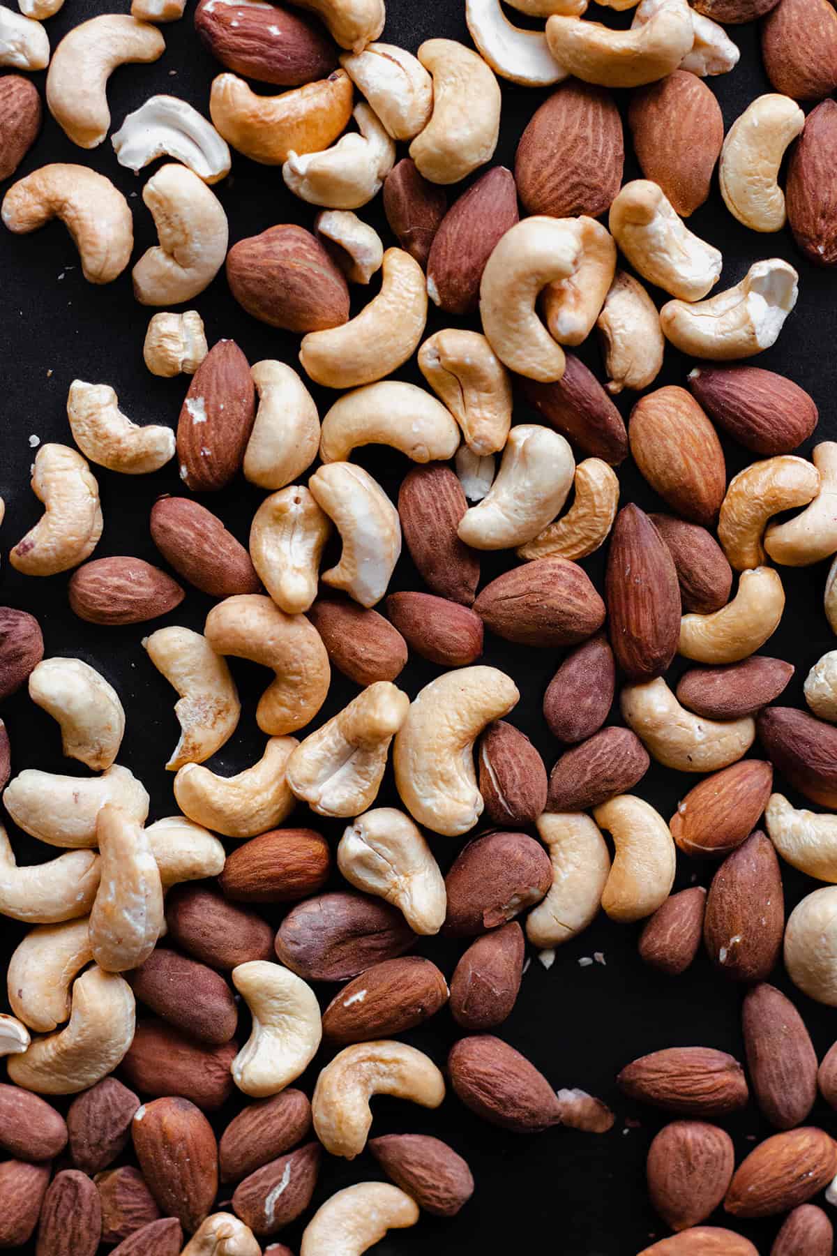 Cashews and almonds on a black background.