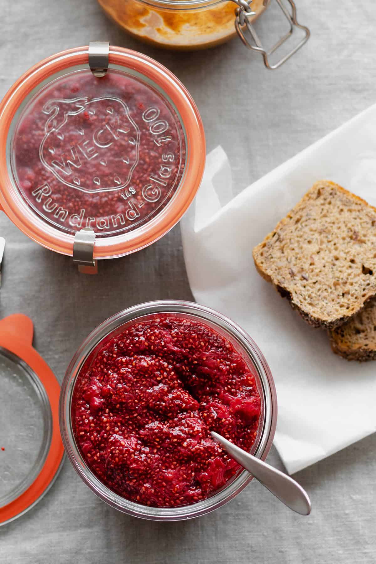 Strawberry Chia Jam in a glass jar with a spoon.