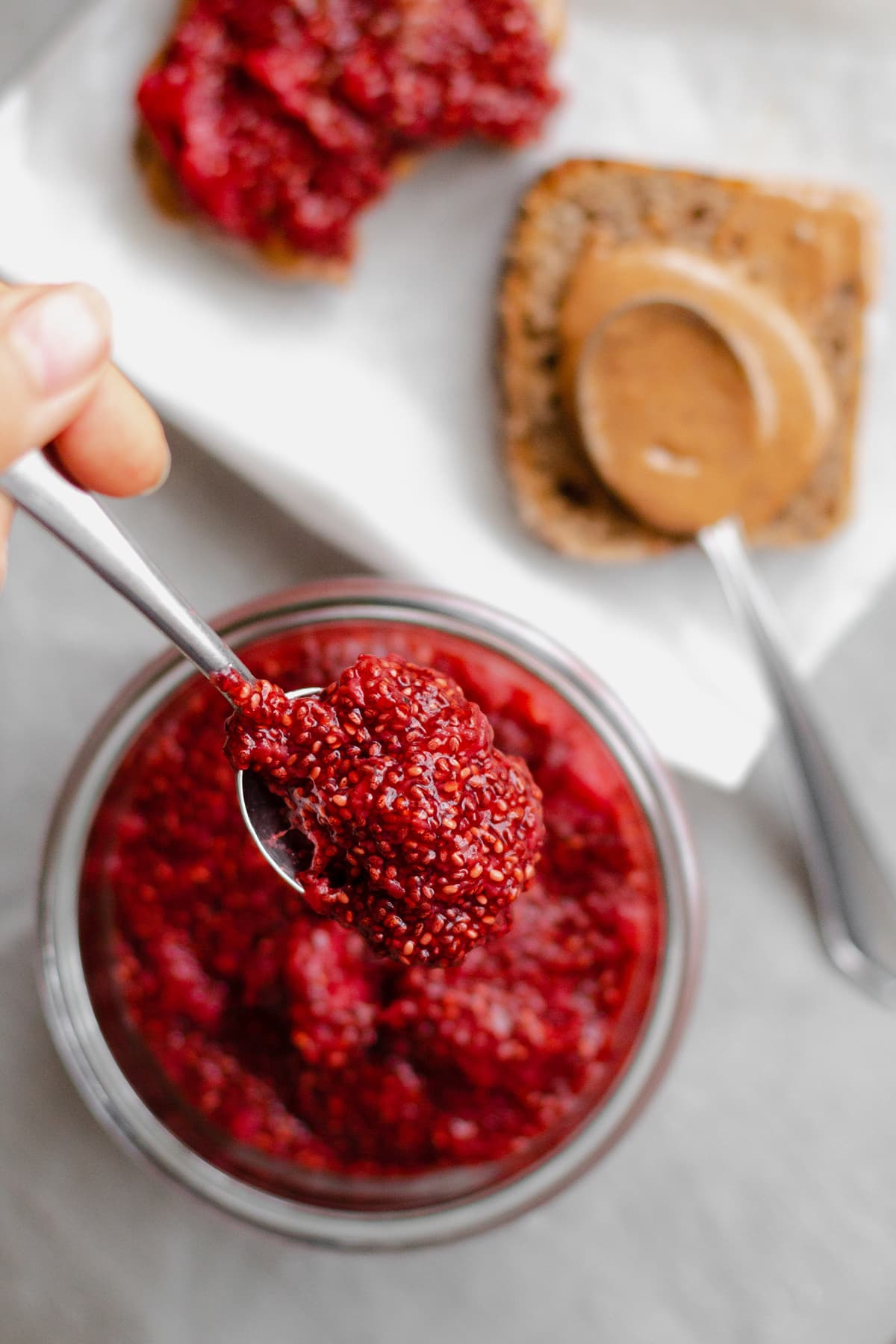 Strawberry Chia Jam in a glass jar with a spoon.