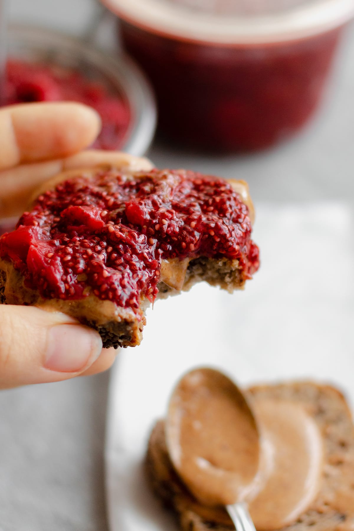 A hand holding a toast with peanut butter and chia jam.