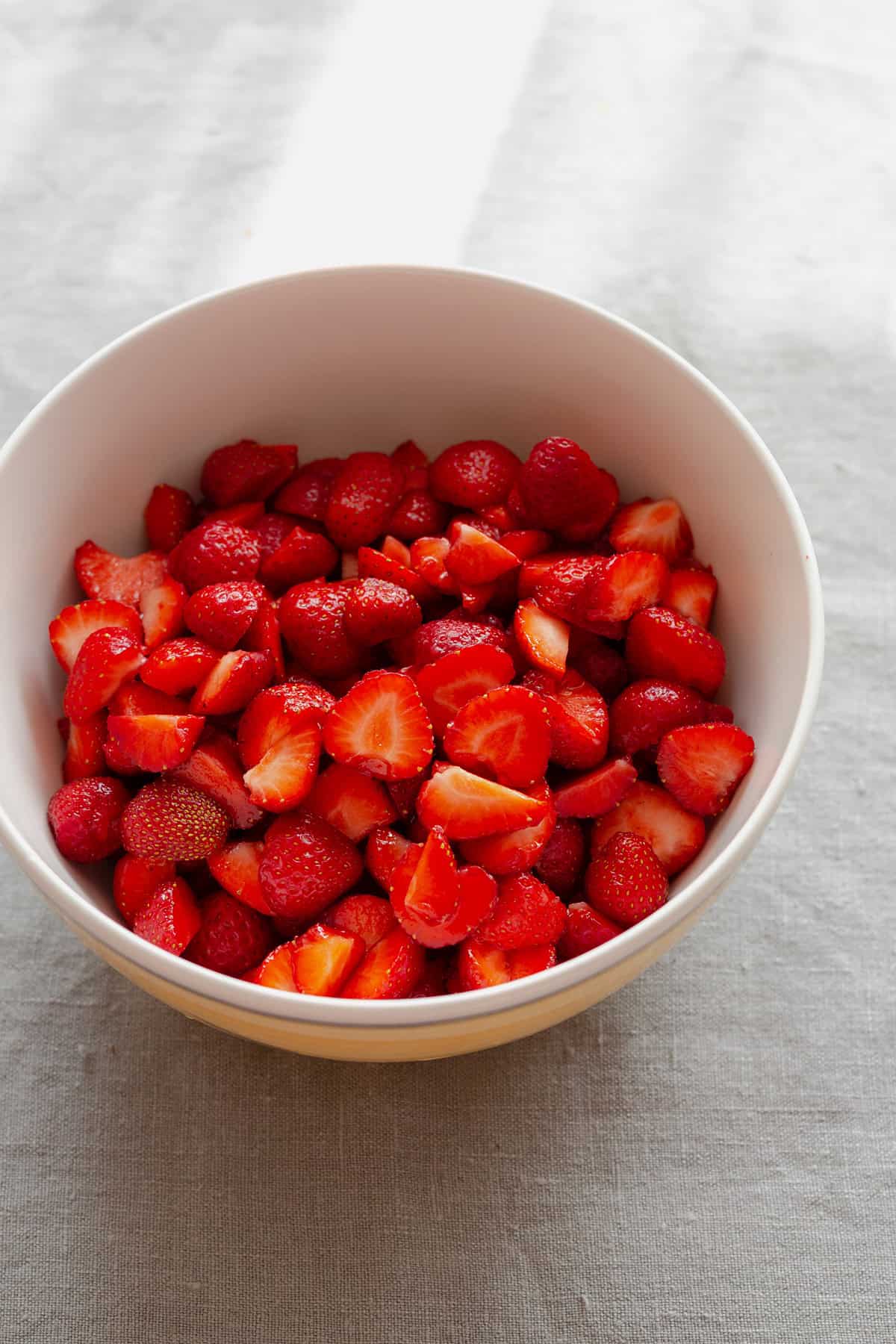 Chopped strawberries in a beige bowl.