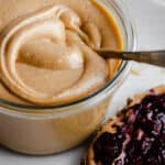 Wild Jungle Peanut Butter in a glass jar on a white plate.